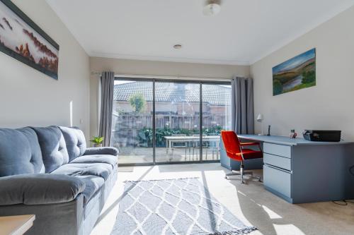 a living room with a couch and a desk and a red chair at Point Cook Spacious Maison in Point Cook