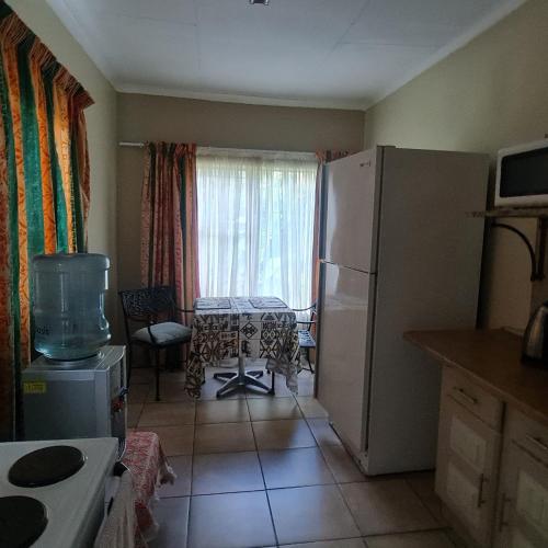 a kitchen with a refrigerator and a table and a window at Capital Hill Stay at Spa in Pretoria
