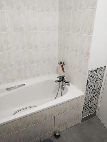 La salle de bains est pourvue d'une baignoire blanche et d'un mur en carrelage. dans l'établissement Superb modern apartment, à Clichy