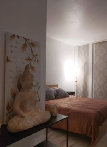 une statue assise sur une table à côté d'un lit dans l'établissement Superb modern apartment, à Clichy