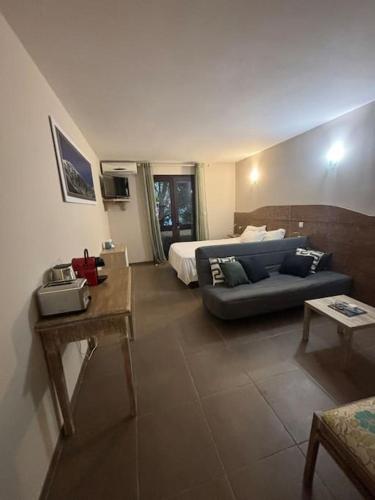 un salon avec un canapé et un lit dans l'établissement Studio 4 personnes avec piscine - Le petit Empereur, à Marine de Sisco