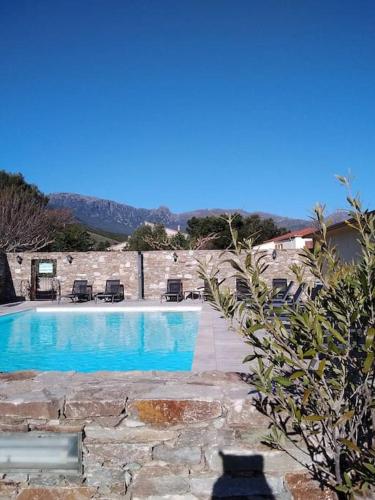 une piscine avec des chaises à côté d'un mur de pierre dans l'établissement Studio 4 personnes avec piscine - Le petit Empereur, à Marine de Sisco