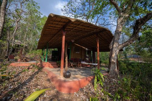 a house with a wooden roof in a forest at Khaama Kethna Eco Sustainable Village in Agonda