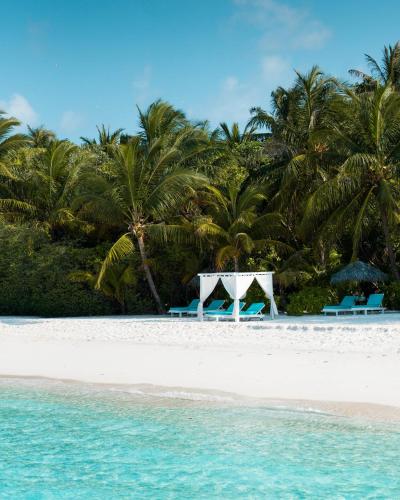 two tables and chairs on a beach with palm trees at Adaaran Select Meedhupparu - with Dine around Premium All inclusive - 24 hours in Meedhoo
