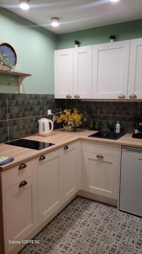 a kitchen with white cabinets and a sink at Apartament'' Leśny przy parku'' in Nałęczów