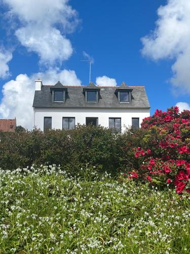 une maison blanche avec des fleurs devant elle dans l'établissement Villa Le Bolzen, à Lézardrieux