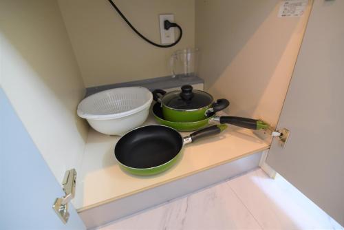 a kitchen with two pans and a bowl on a shelf at QUAYSIDE SAKURAGICHO 201 in Hiranumachō