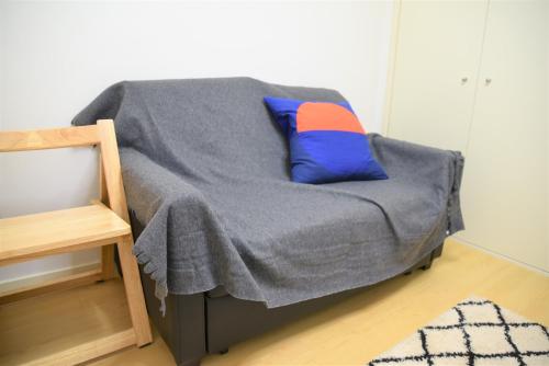 a bed with a blue and orange pillow on it at QUAYSIDE SAKURAGICHO 201 in Hiranumachō