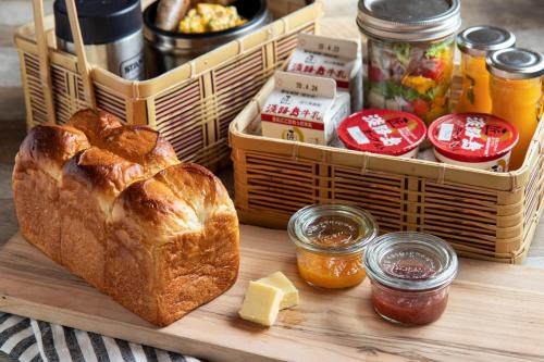 a wooden table with a basket of bread and condiments at Villa and Glamping Lazy Inn in Awaji