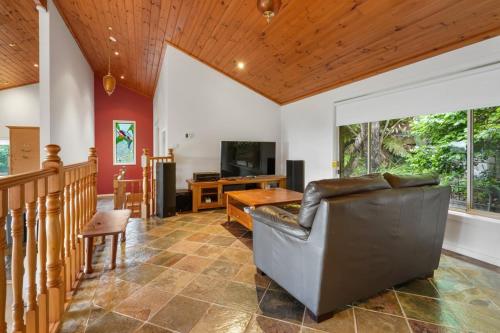 a living room with a couch and a television at Embrace Nature's Beauty in Ferny Creek in Ferny Creek