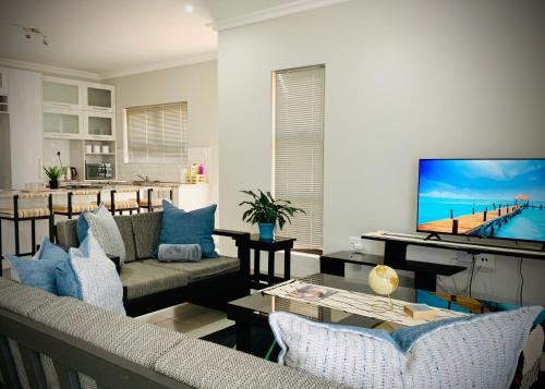 a living room with a couch and a flat screen tv at Olive Villa Self Catering Apartments in Swakopmund