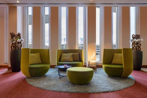 a lobby with two chairs and a table and windows at Novotel Freiburg am Konzerthaus in Freiburg im Breisgau