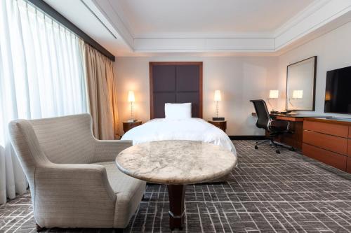 a hotel room with a bed and a chair and a table at Lotte Hotel Busan in Busan