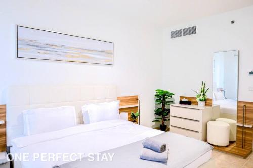 ドバイにあるStunning View 1 Bedroom Apartment Pool & Gymのベッドが2つあり、壁に絵が飾られている寝室