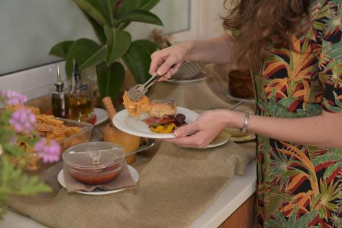 a woman holding a plate of food on a counter at Georgia's Garden by Omilos Hotels in Amoudara Herakliou
