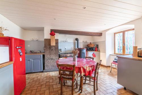 une cuisine avec une table et un réfrigérateur rouge dans l'établissement La Maison de Freda - Maison avec vue montagne, à Beauregard