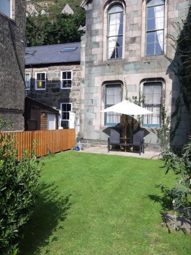 a patio with an umbrella in front of a house at Ground Floor Barmouth Centre Apartment With Garden in Barmouth
