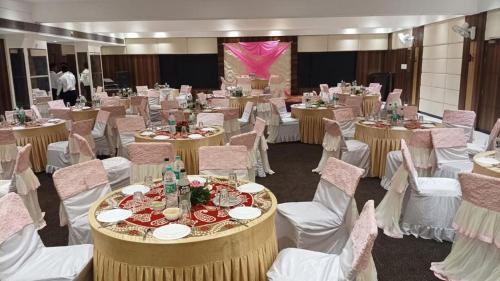 a banquet hall with white chairs and tables and tablesktop at The Four Seasons Recreation in Jālgaon