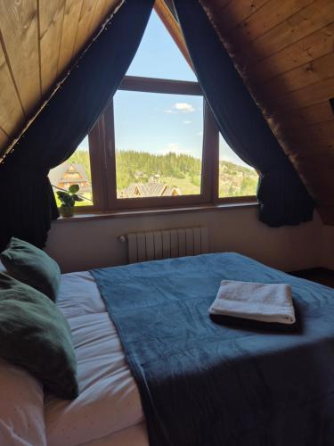 a bed with a towel on it in front of a window at Willa na Skarpie in Kościelisko
