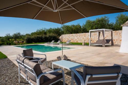 een terras met een tafel, stoelen en een parasol bij PALACHARME - Trulli Luxury in Alberobello