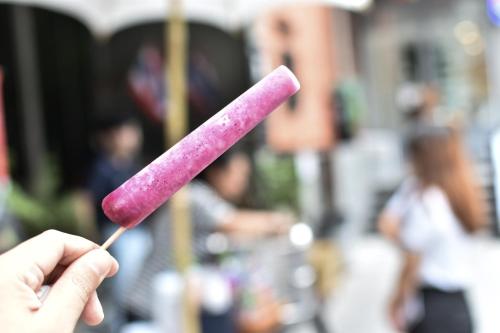 a person holding a piece of food on a stick at THA City Loft by TH District in Bangkok