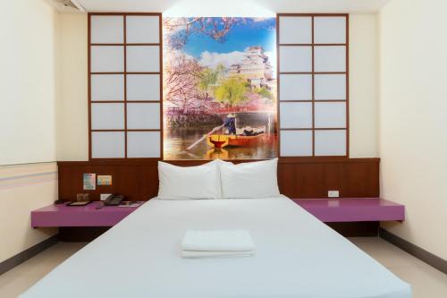 a bed in a room with a painting on the wall at โรงแรมนั่งเล่น in Chon Buri