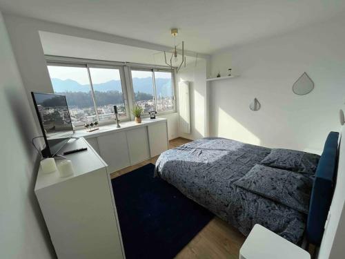 a bedroom with a bed and a desk and windows at Plein centre-ville T2 refait à neuf in Aix-les-Bains