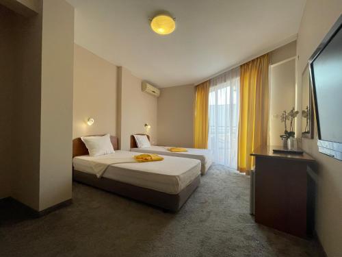 a hotel room with two beds and a flat screen tv at Alatoni Beach Hotel in Sozopol
