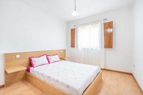 a white bedroom with a bed with pink pillows at Cantinho dos Fernandes in Ponte da Barca