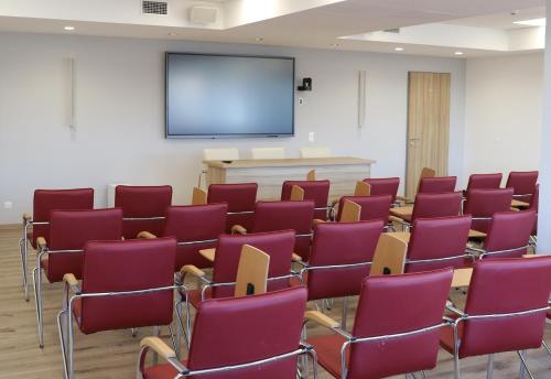 a lecture room with red chairs and a screen at Budafoki Sporthotel in Budapest