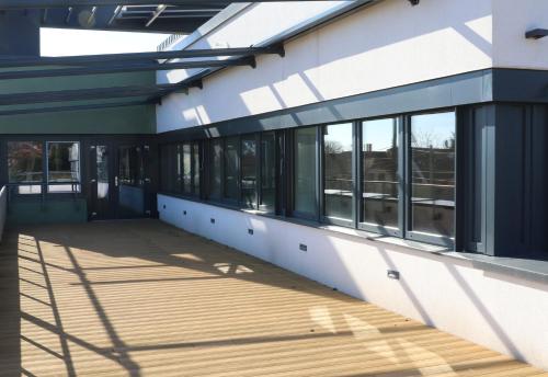 a large building with windows and a wooden deck at Budafoki Sporthotel in Budapest