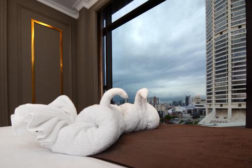 two white swans sitting on a bed in a hotel room at The Granite Luxury Hotel Penang in George Town