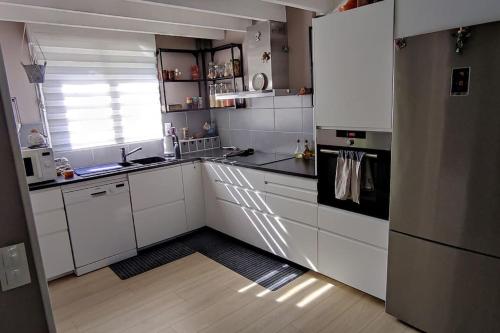 a kitchen with white cabinets and a black refrigerator at Maison proche de tout in Saint-Herblain