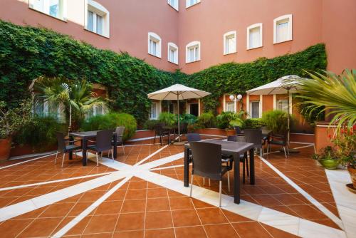 a patio with tables and chairs and a green wall at Crisol Chiclana in Chiclana de la Frontera