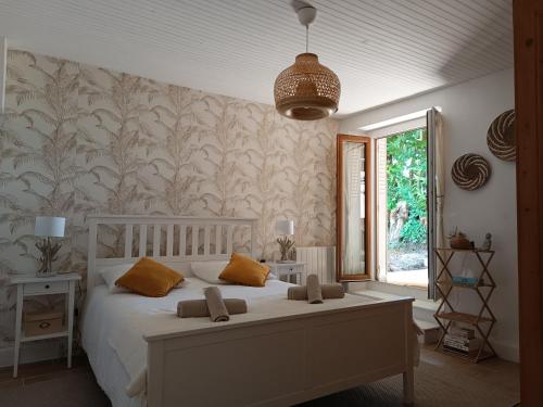 une chambre avec un grand lit blanc avec des oreillers orange dans l'établissement Maison berrichonne WiFi jardin linge, à Aigurande