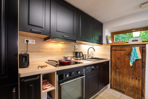 - une cuisine avec des placards noirs, un évier et une cuisinière dans l'établissement Le Carot, à Campan