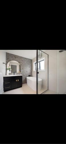 a bathroom with a tub and a sink and a mirror at Modern Central Auckland in Auckland