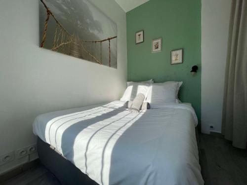 une chambre avec un grand lit avec des draps blancs dans l'établissement Marseille centre - wifi - lave et sèche linge - calme - cuisine, à Marseille