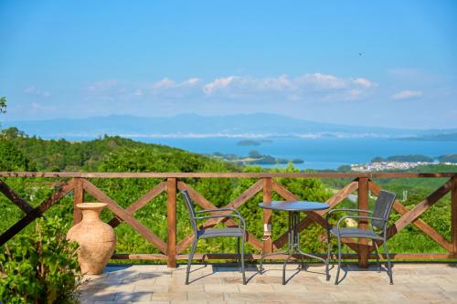 a patio with two chairs and a table and a vase at 長崎の丘に浮かぶ天空テラス Villa 森の魔女 ,Villa Forest Witch in Nagasaki
