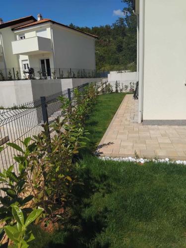 a fence in front of a house with a yard at Apartment Tanya in Rijeka