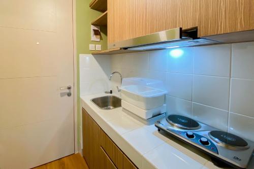a small kitchen with a sink and a stove at Fully Furnished with Cozy Design Studio Apartment Tokyo Riverside PIK 2 By Travelio in Rawalembang