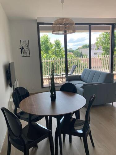 un salon avec une table, des chaises et un canapé dans l'établissement F2 neuf cosy et élégant avec terrasse, parking, WIFI, à Chamalières