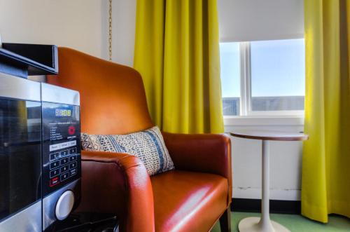 a living room with a chair and a microwave at Mylo Hotel in Daly City