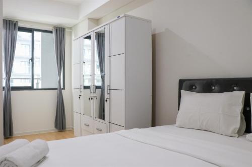 a white bedroom with a large white cabinet and a bed at Comfort 2BR at Daan Mogot City Apartment By Travelio in Jakarta