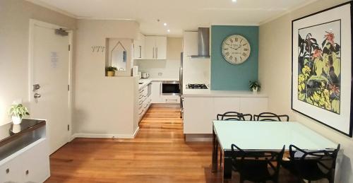 a kitchen and dining room with a table and a clock on the wall at ReadySet Apartments at Southbank Condos in Melbourne