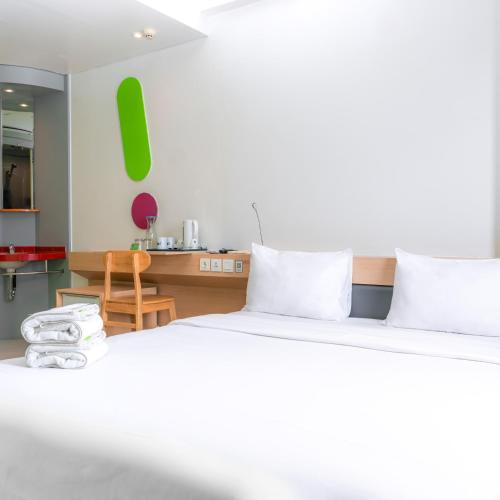 a bedroom with two beds and a desk with a chair at POP! Hotel Banjarmasin in Banjarmasin