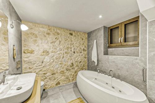 a bathroom with a tub and a sink and a mirror at Komody in Delfoi
