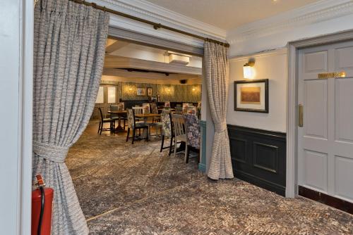 a dining room with curtains and a table and chairs at Blue Bell Lodge Hotel in Middlesbrough