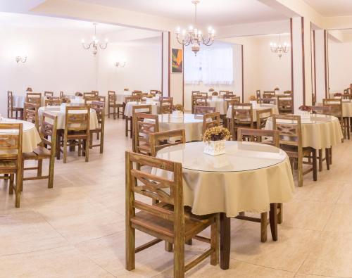 uma sala de jantar com mesas e cadeiras e uma sala com lustres em Hotel Fabris em Nova Friburgo