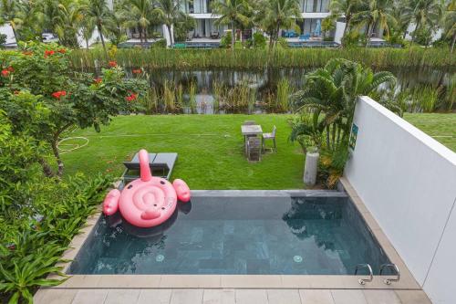 a swimming pool with a pink pig in a backyard at Villa 4 Phòng Ngủ Sanctuary Hồ Tràm - Cách Biển 70m in Ho Coc